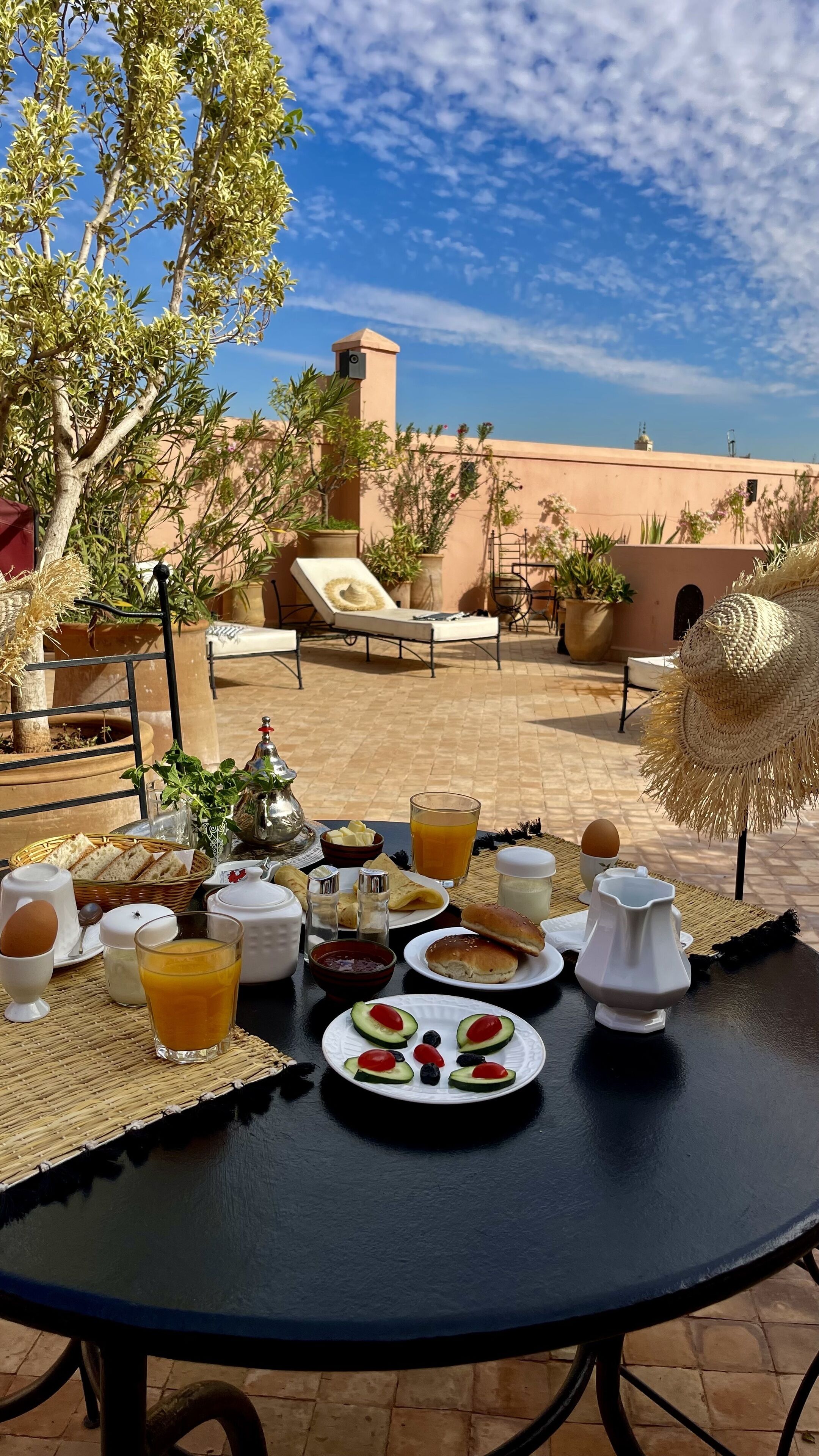 An outdoor breakfast setup with a table, breakfast items, and a view of the sky and buildings.