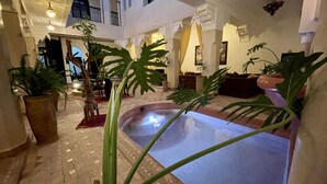 A spacious indoor area with a central water feature, potted plants, and a staircase leading to an upper level. - Riad Dar Foundouk & Spa (Marrakech)