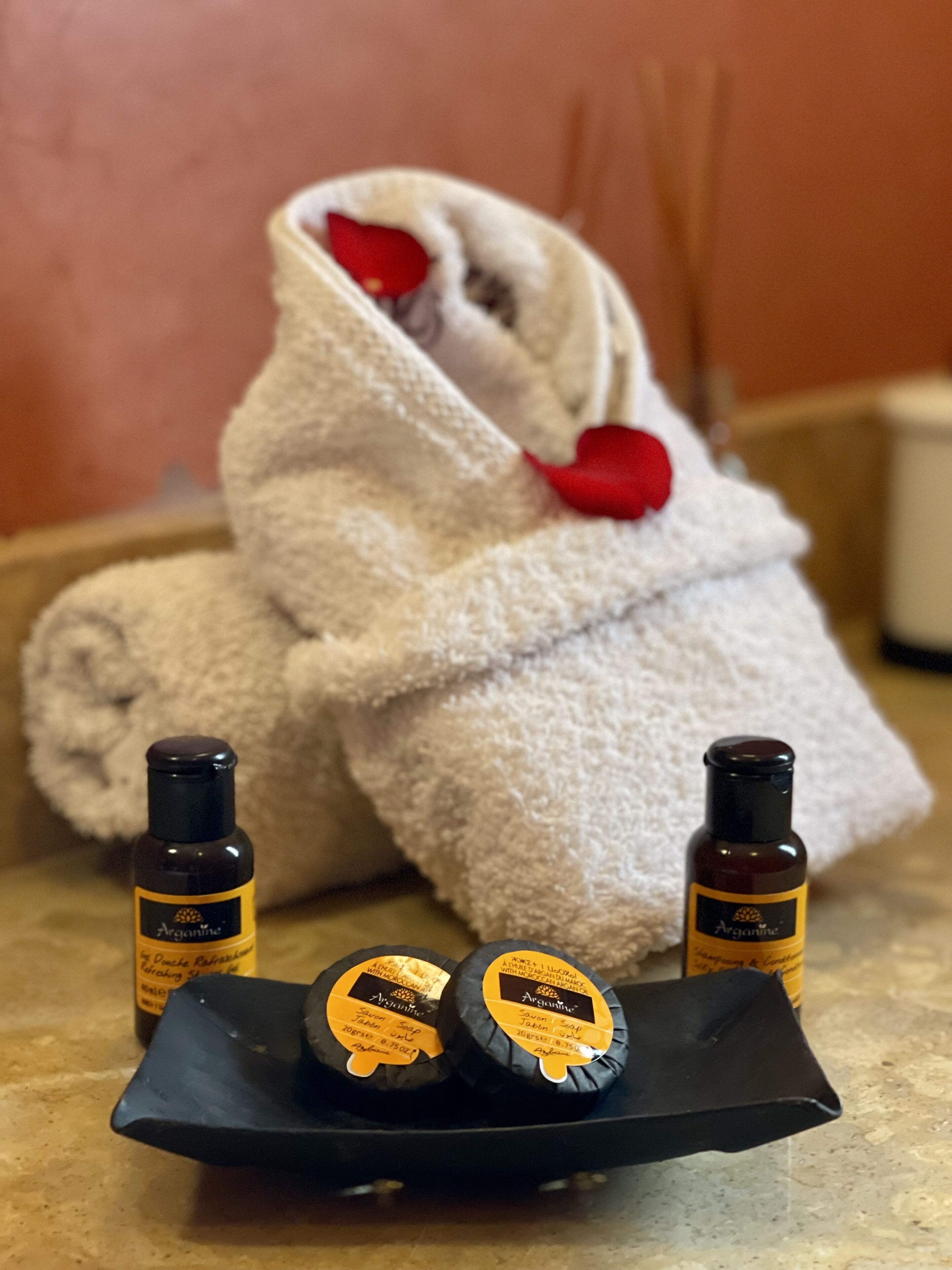 A towel, two bottles of soap, and a tray on a countertop.