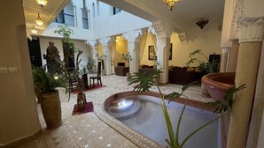 A spacious courtyard with a central water feature, potted plants, and seating areas. - Riad Dar Foundouk & Spa (Marrakech)
