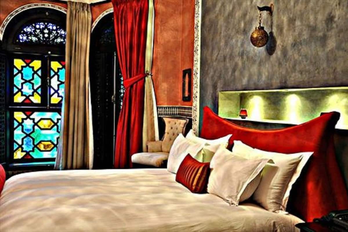 A hotel room with a bed, a chandelier, and a stained glass window.