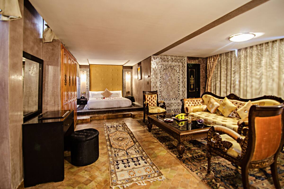 A hotel room with a bed, a sofa, a coffee table, and a carpet.