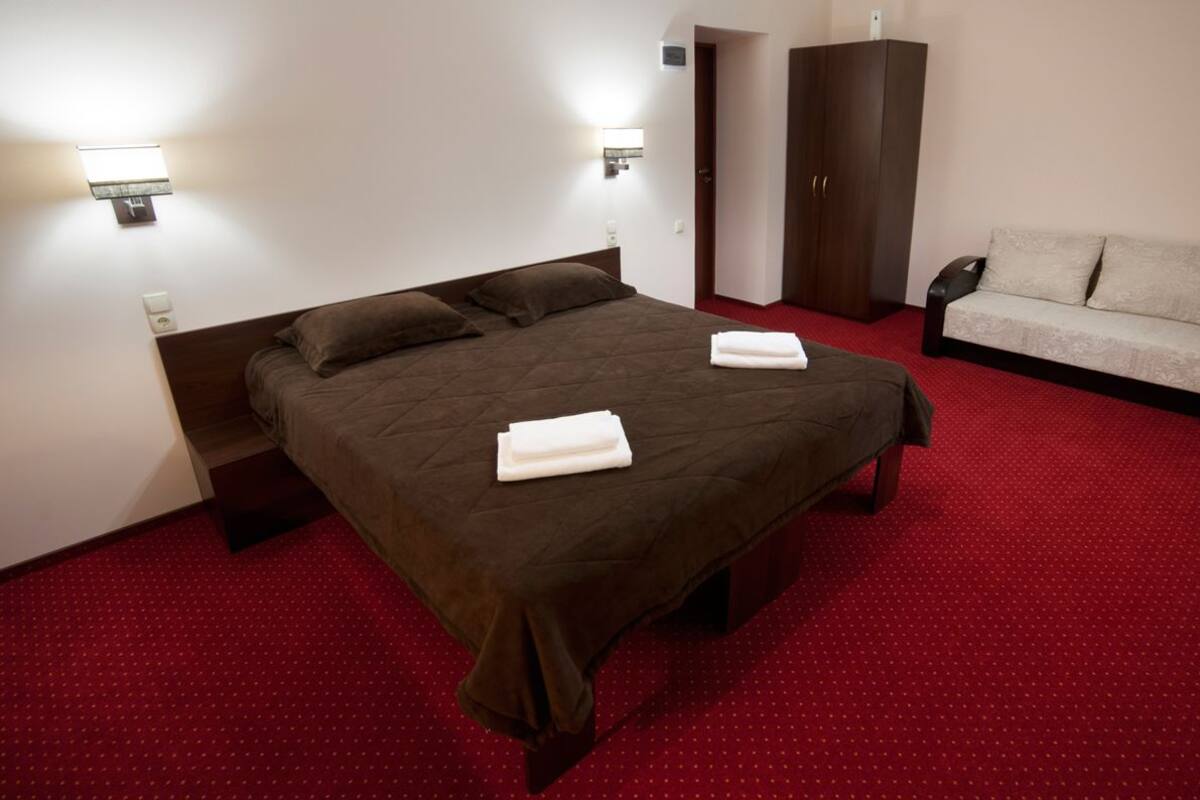 Ein Hotelzimmer mit einem großen Bett, zwei Nachttischlampen, einem Kleiderschrank und einem Sofa.