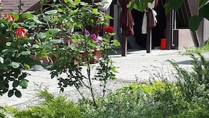 A garden with a variety of plants and flowers, including roses, in front of a building with a brick facade and a window with curtains. - Hotel 12 (Kharkiv)