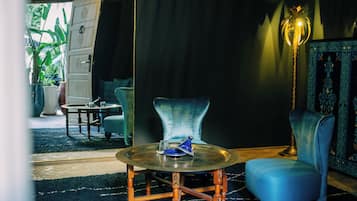 A room with a round table, a blue chair, a lamp, and a cabinet.