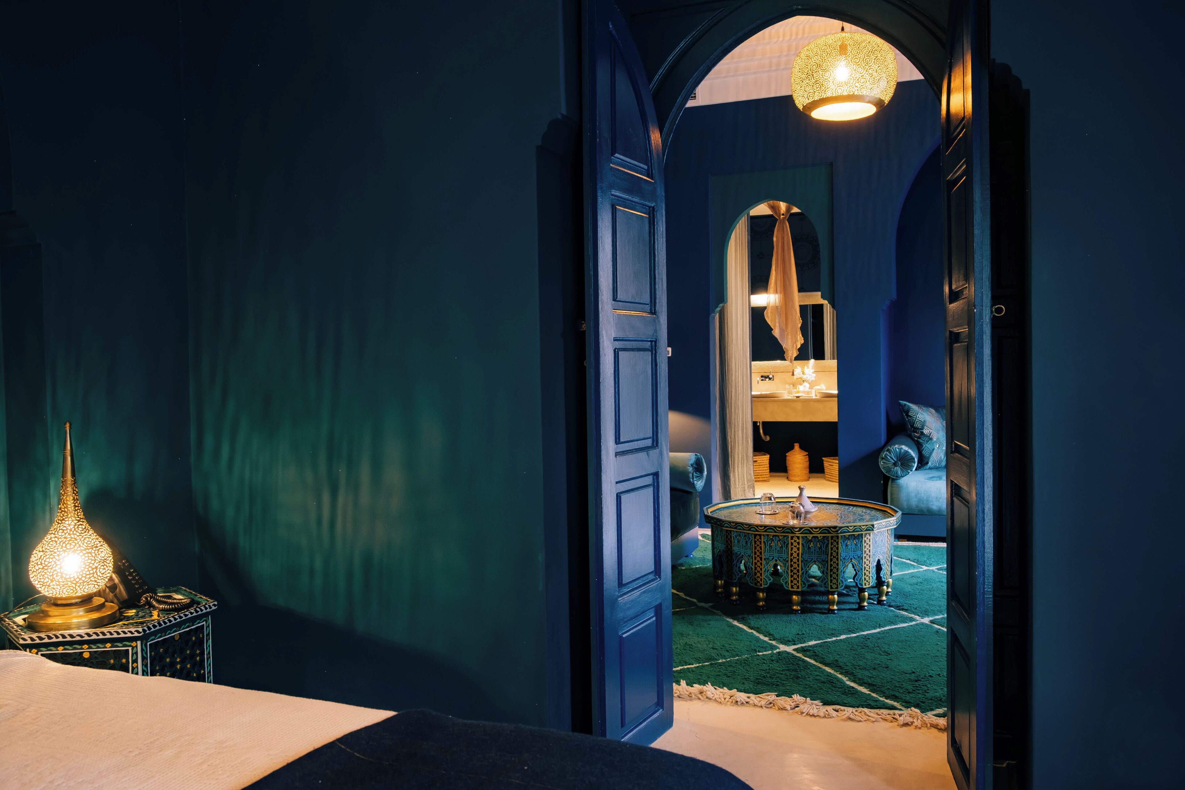 A hallway with a blue door, a patterned floor, and a table with a lamp.