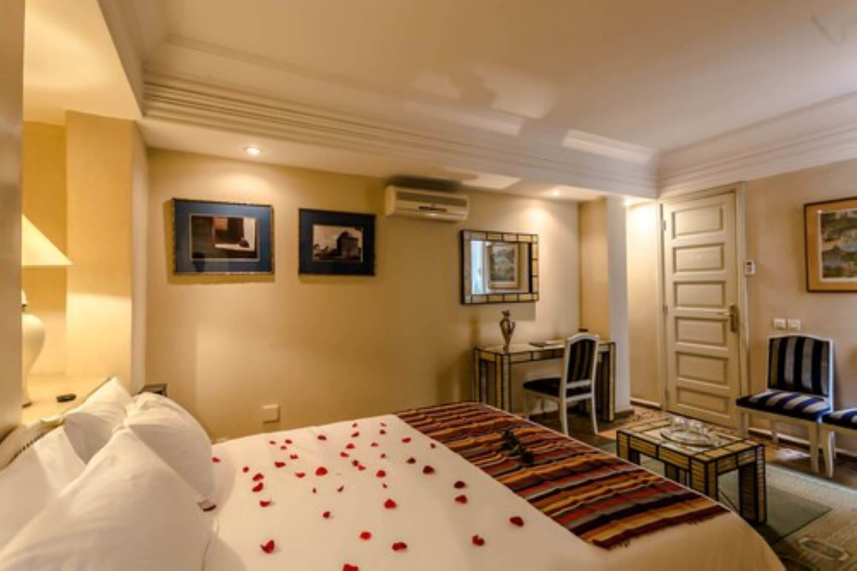 A hotel room with a bed, a desk, a chair, and a small table.