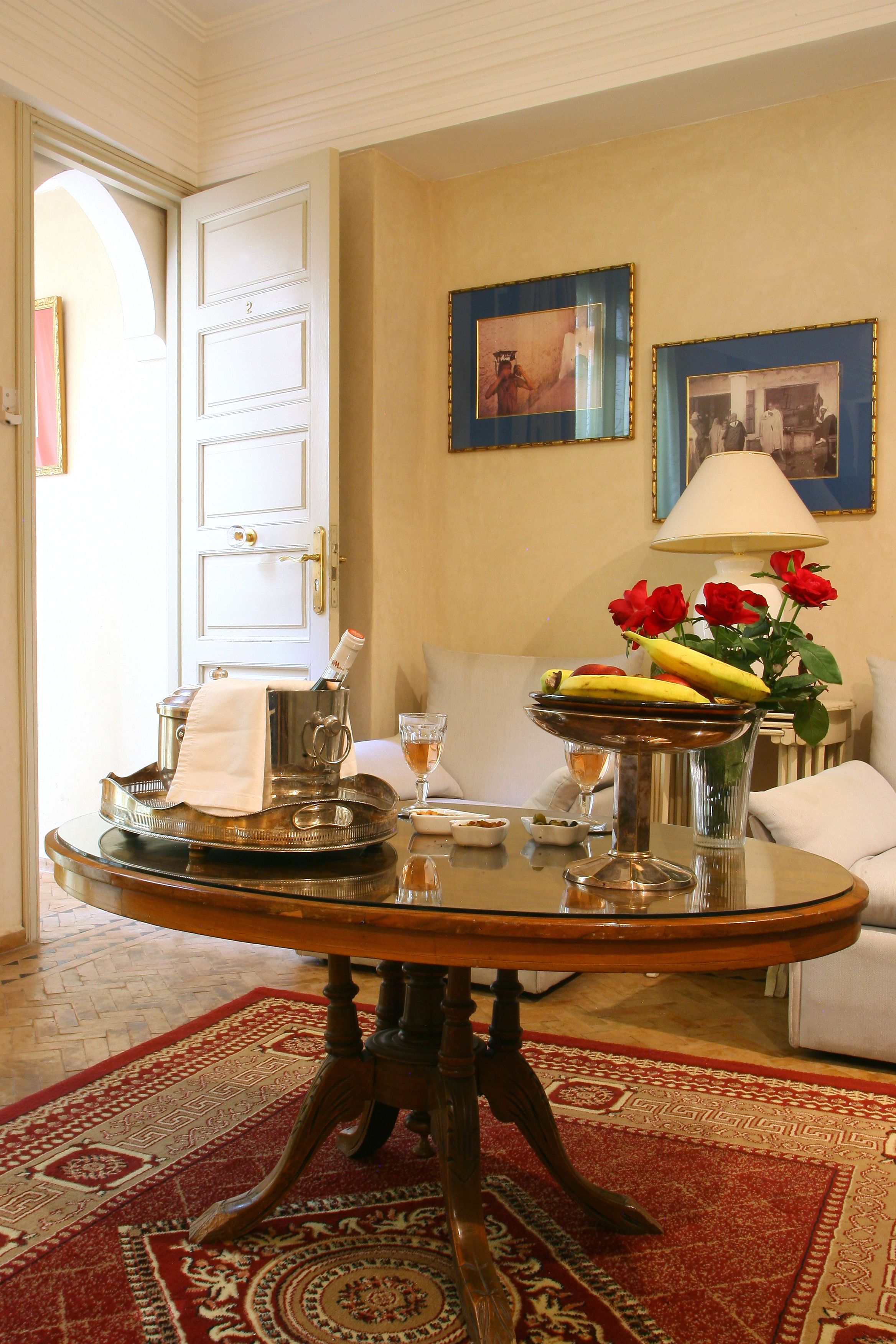A dining area with a round table, a white door, and a red and beige patterned rug.