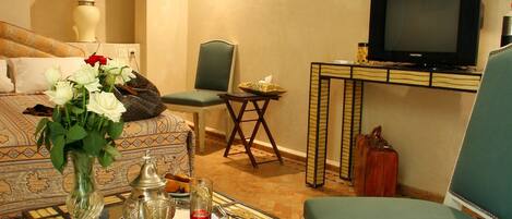 A living room with a sofa, a green armchair, a coffee table, a television, and a wall-mounted air conditioner.