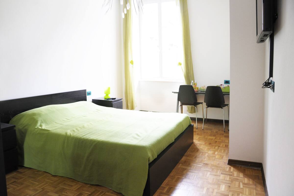 Um quarto com uma cama, uma escrivaninha e uma cadeira.