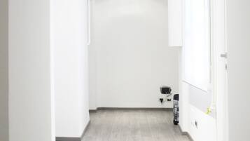 A narrow hallway with light-colored wooden flooring and white walls.