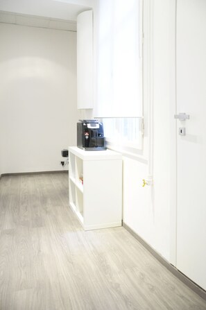 Compact room with a wardrobe and cabinet, featuring a microwave and a window.