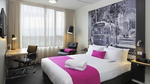 A hotel room with a large bed, a desk with a chair, a chair with a pillow, a desk lamp, and a wall-mounted TV. - Mercure Melbourne Therry Street (Melbourne)