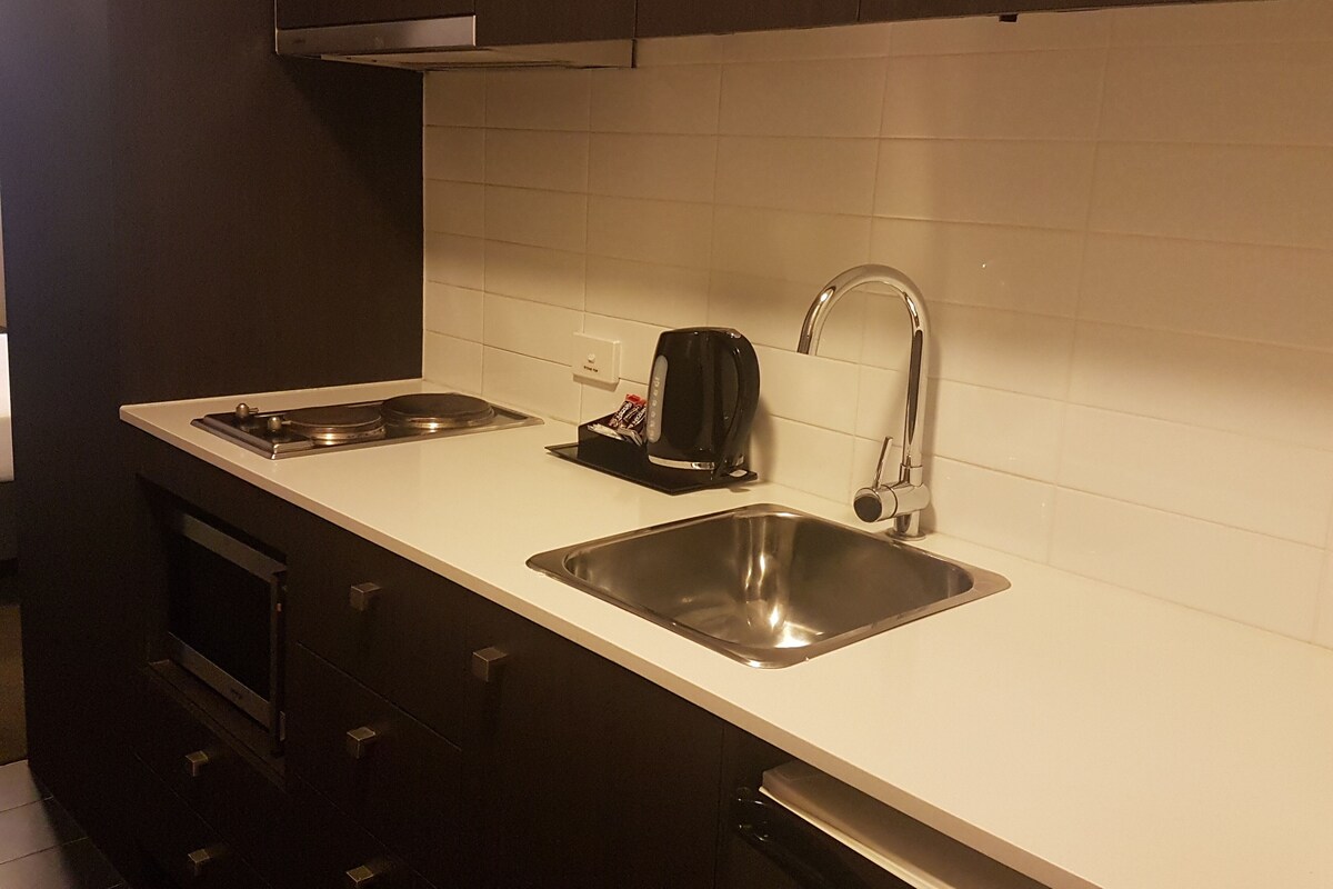 A kitchen with two stainless steel sinks, a black coffee maker, and a built-in oven.