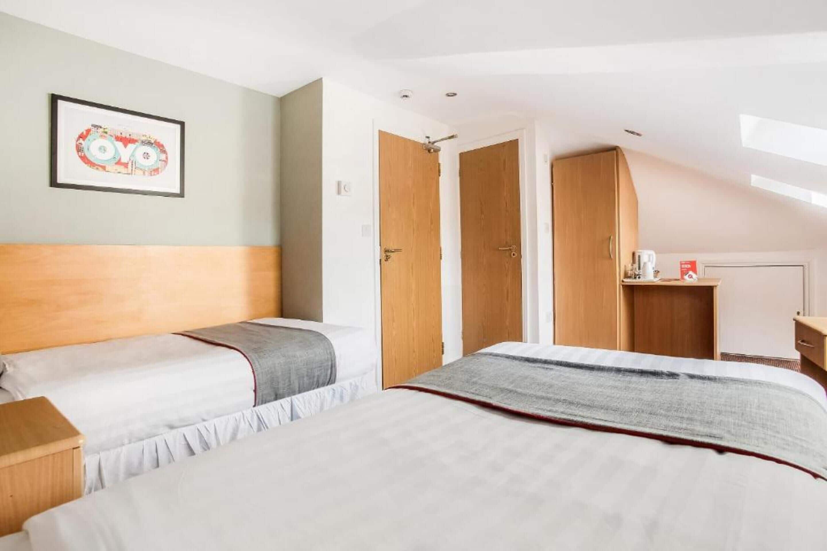 Un dormitorio con dos camas, un cabecero de madera, un cuadro en la pared y un tragaluz.