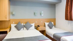 A hotel room with two beds, a wooden headboard, bedside tables, and wall-mounted light fixtures. - London Guest House by OYO - Acton (London)