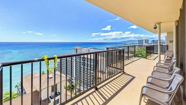 A balcony with a view of the ocean and cityscape, featuring a row of chairs and a decorative garland. - The Imperial Hawaii Resort (Honolulu)