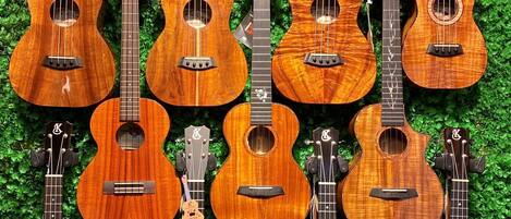 Un grupo de ukeleles frente a un fondo de hojas verdes.