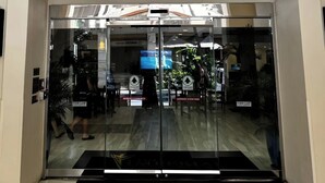 The entrance to The Imperial Hawaii Resort with a clear glass facade, automatic sliding doors, and a black mat at the entrance. - The Imperial Hawaii Resort (Honolulu)