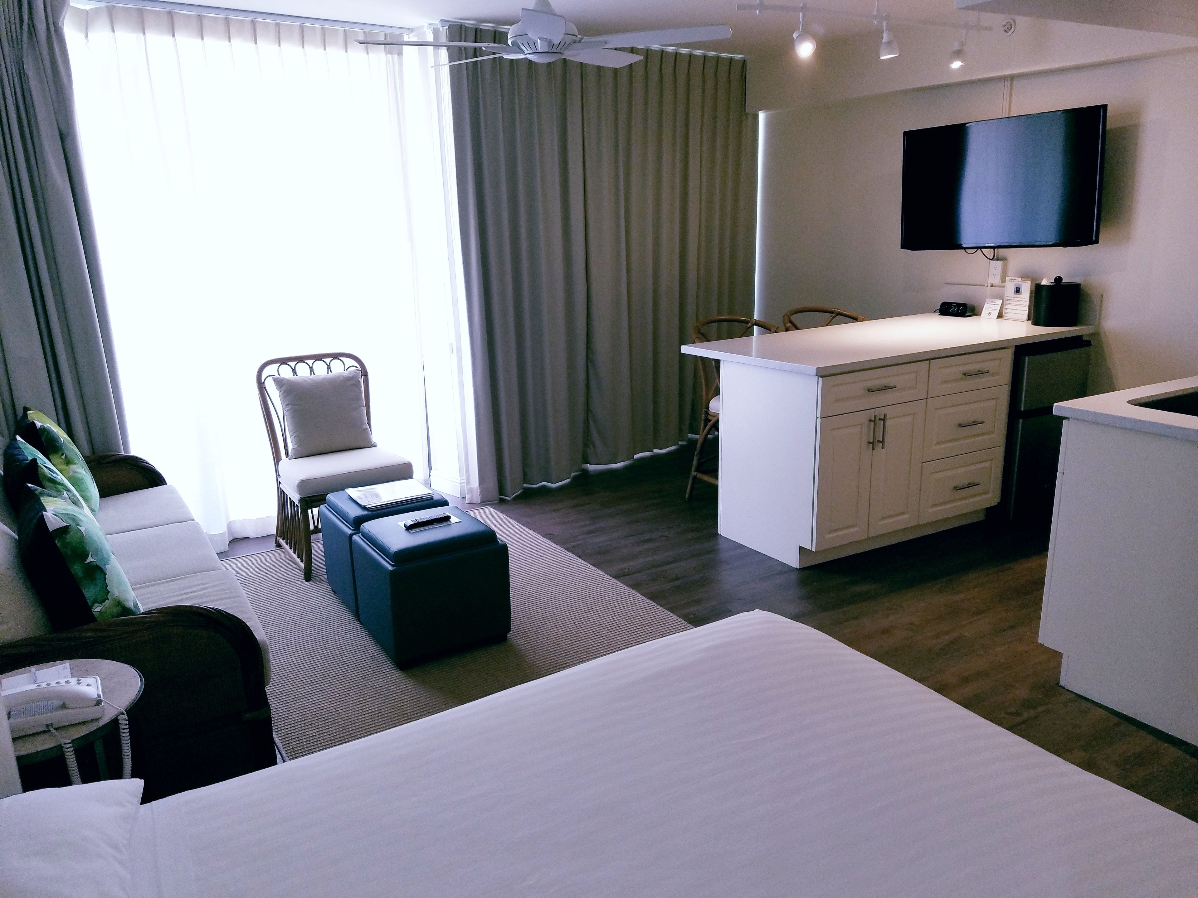 Une chambre d’hôtel avec un lit, un bureau, une chaise, une télévision et une fenêtre avec des rideaux.