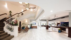 A spacious lobby with a curved staircase, wooden seating, and a reception desk. - The Imperial Hawaii Resort (Honolulu)