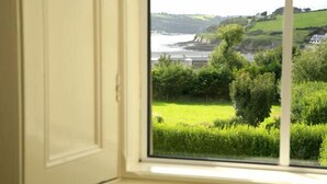 A window with a view of a grassy field, trees, and a body of water. - Glendine Country House (Arthurstown)