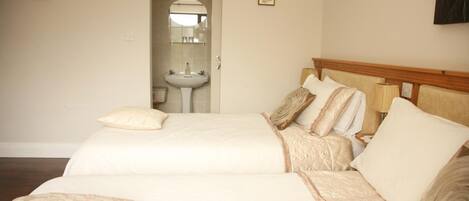 A hotel room with two beds, a bathroom with a sink, and a mirror.