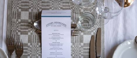 A table set with a menu, cutlery, and glasses, indicating a dining arrangement.