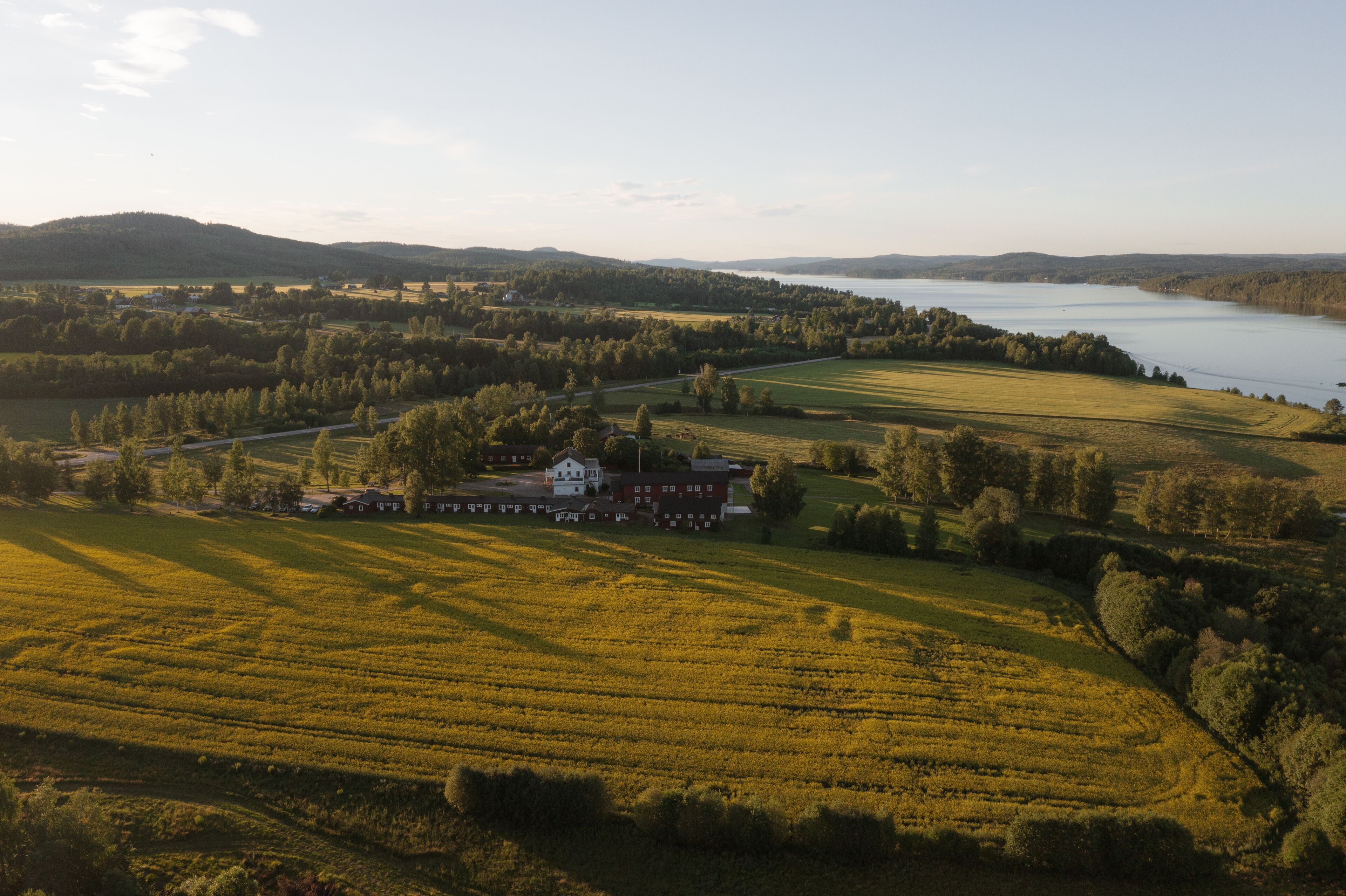 A large estate with expansive fields and a lake in the background.