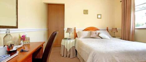 Habitación de hotel con cama, escritorio, silla y armario.