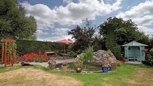 Un jardín con un estanque, un pabellón y una pérgola.