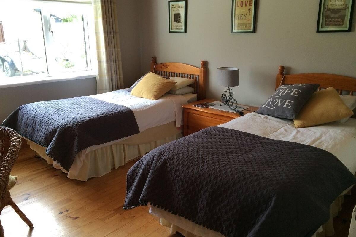 A hotel room with two beds, wooden headboards, and a window with curtains.