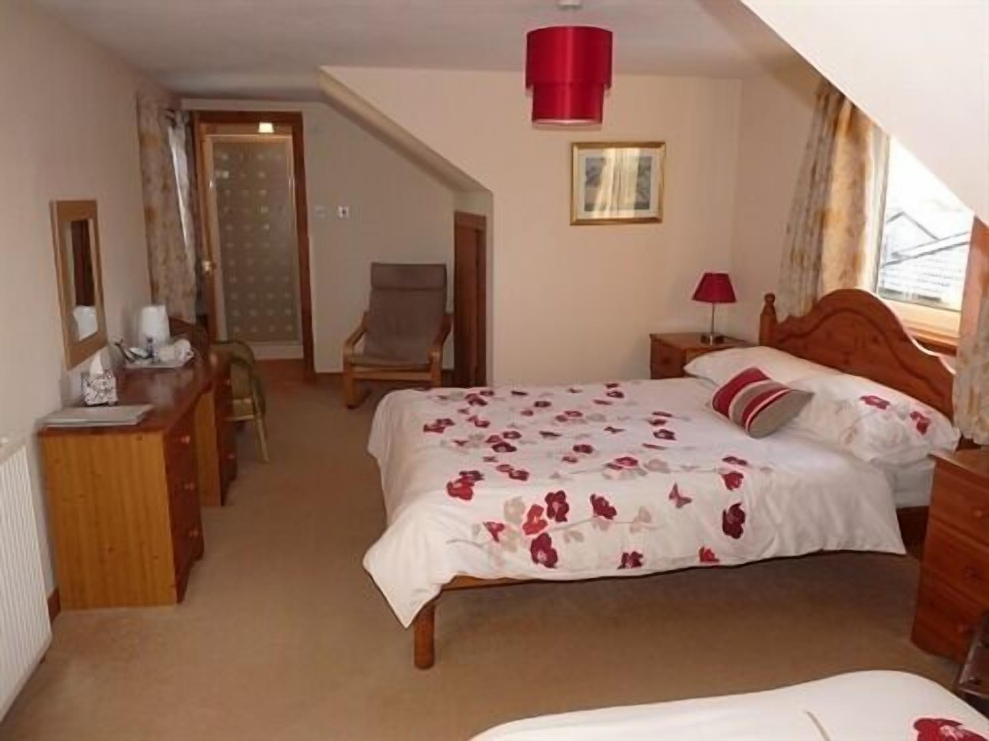 A bedroom with a bed, a chair, a desk, and a window.