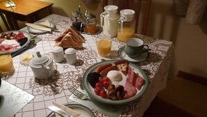 Een ontbijttafel gedekt met borden eten, een karaf, kopjes en een kan.