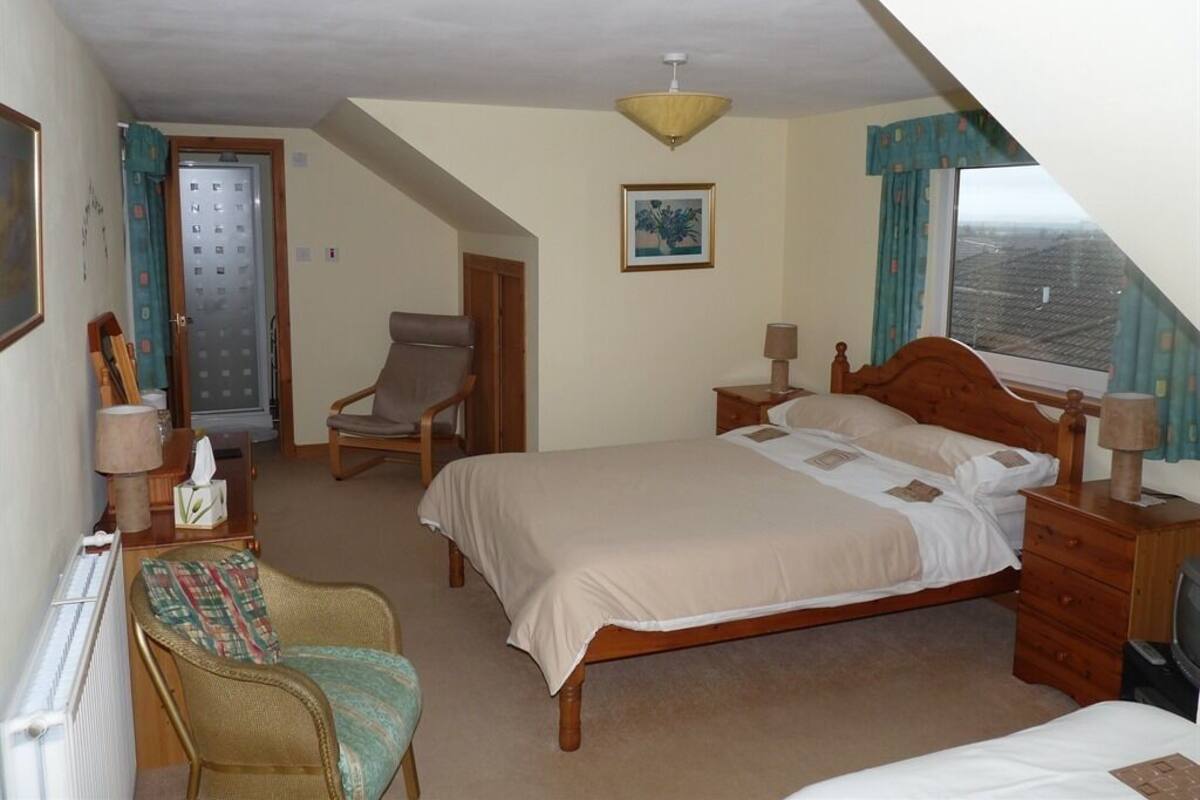 Un dormitorio con una cama, una silla, un escritorio y una ventana.