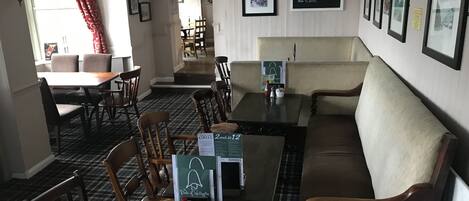 A restaurant with a checkered floor, wooden furniture, and a chalkboard menu.