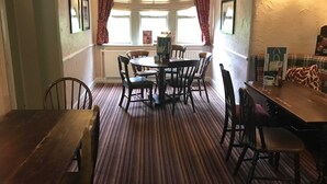 A dining area with a round table and chairs, a radiator, and a window with curtains. - Duke of Wellington (Matlock)