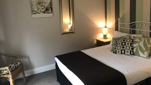A bedroom with a bed, a nightstand, a chair, and two wall-mounted mirrors. - Duke of Wellington (Matlock)