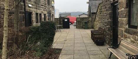 A narrow stone pathway leading to a building with a red van parked outside.