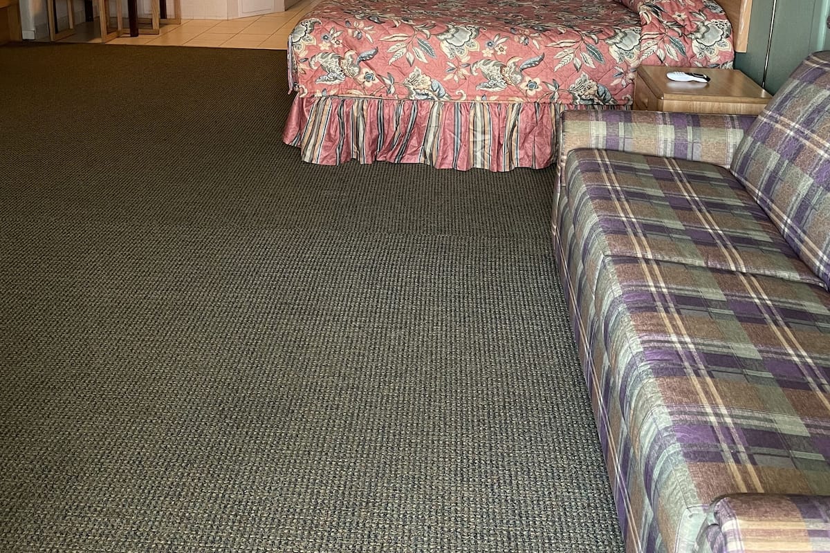 Une chambre d’hôtel comprenant un lit, un canapé, un bureau avec une chaise, un miroir et une lampe.