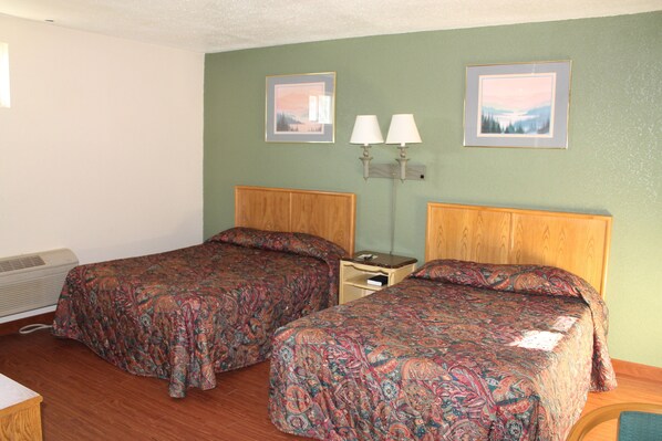 A room with two beds, a nightstand with lamps, and two framed pictures on the wall. - American Motor Inn (Rock Island)