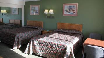 A hotel room with two beds, a desk, and a chair. There are wall-mounted lamps and framed pictures on the walls.