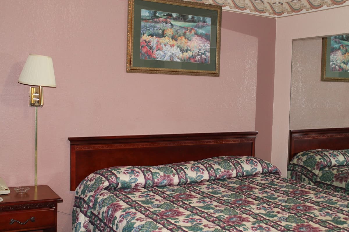 Une chambre à coucher avec une tête de lit en bois, une table de chevet avec une lampe et une couvre-lit à motifs floraux.