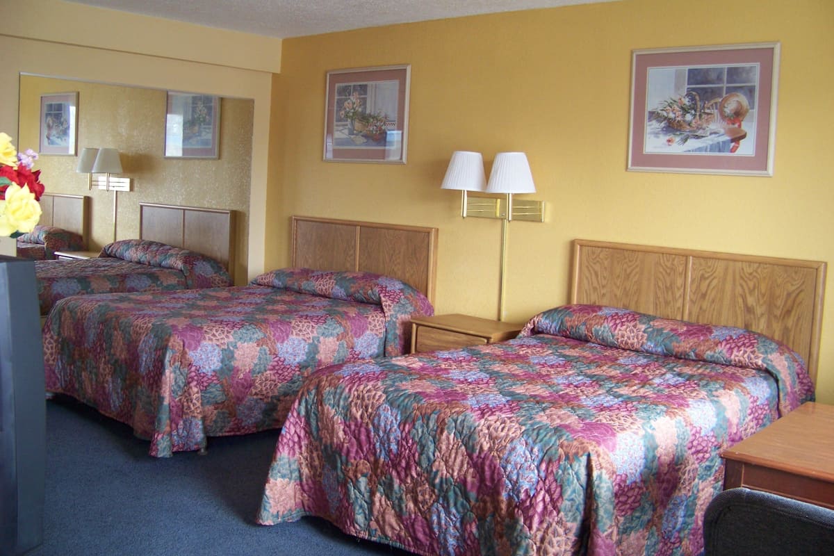 Une chambre d’hôtel avec deux lits, un bureau, une chaise, une lampe et un miroir.