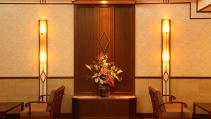 A corner room with a wooden cabinet, two chairs, a small table, and a vase of flowers. - Hotel Oak Forest (Hakuba)