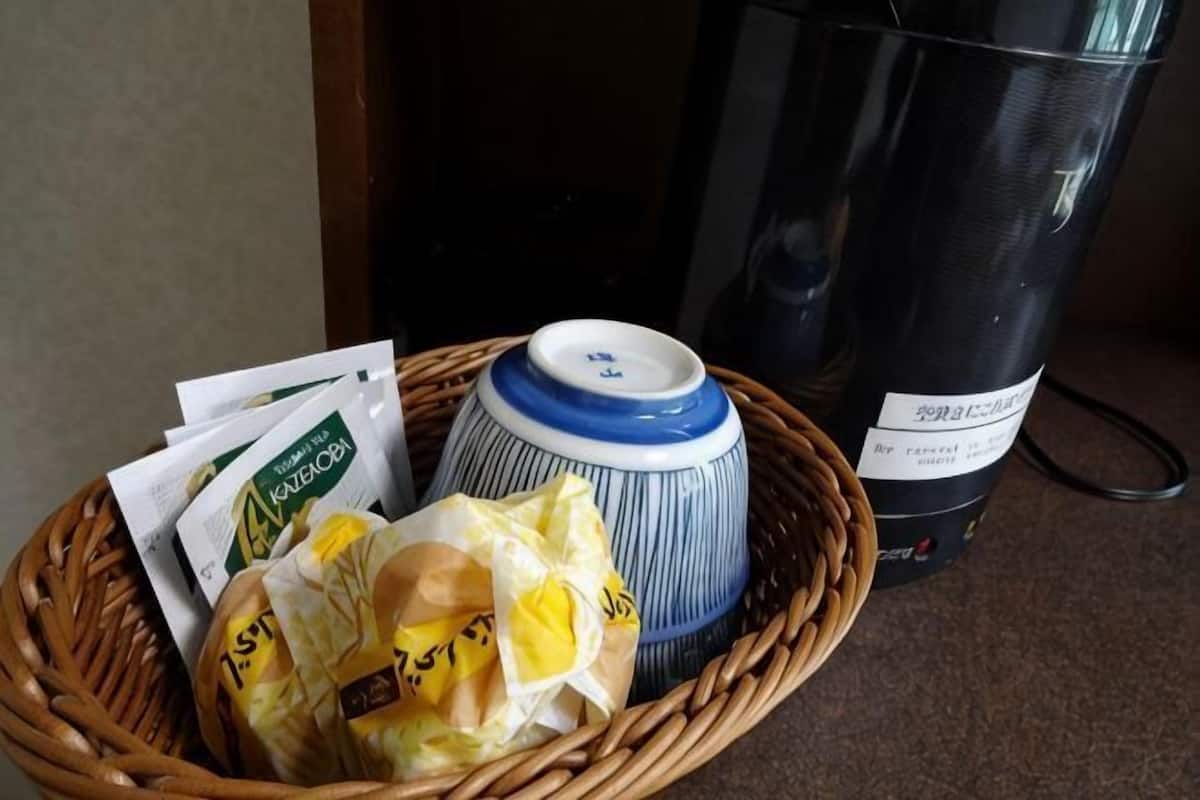 A wicker basket with a blue and white ceramic container, a plastic bag, and a black trash can.