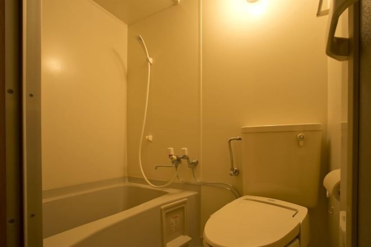Ein kleines Badezimmer mit Badewanne, Toilette und Dusche.