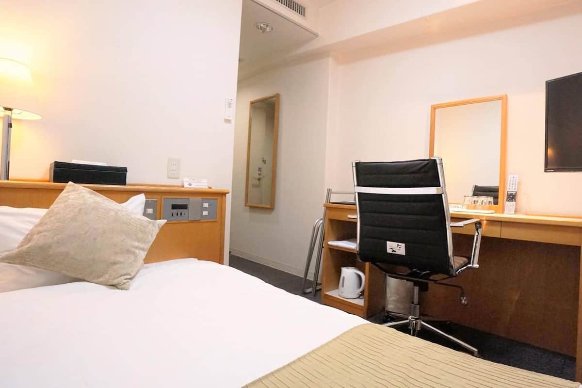 Une chambre d’hôtel équipée d’un lit, d’un bureau, d’une chaise, d’une télévision et d’une machine à café.