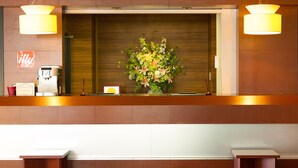 A reception area with a coffee machine, a sign indicating a coffee store is coming soon, and a floral arrangement. - Hotel AreaOne Fukuyama (Fukuyama)