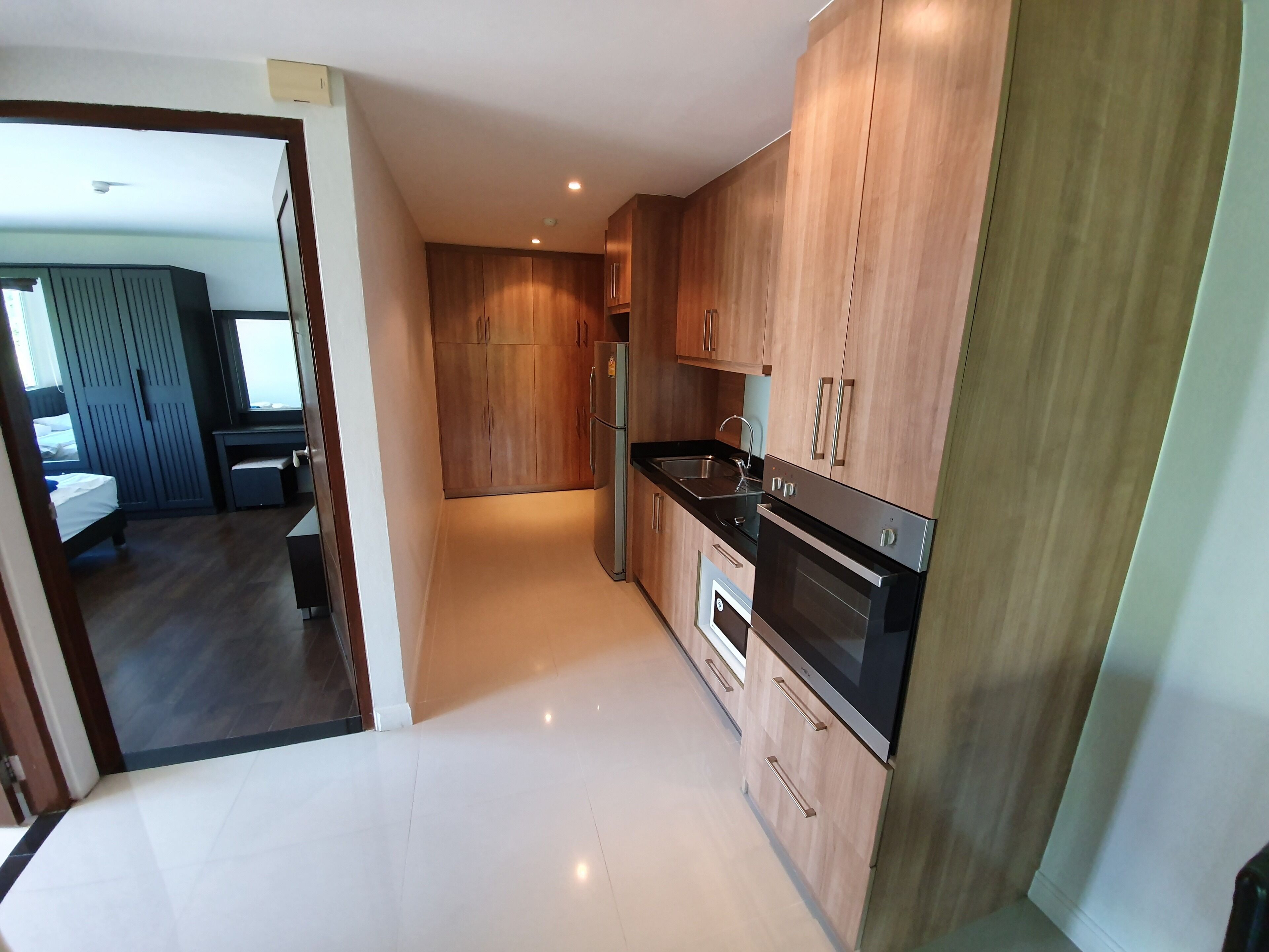 Une cuisine moderne avec des meubles en bois, un réfrigérateur en acier inoxydable et un four encastré.